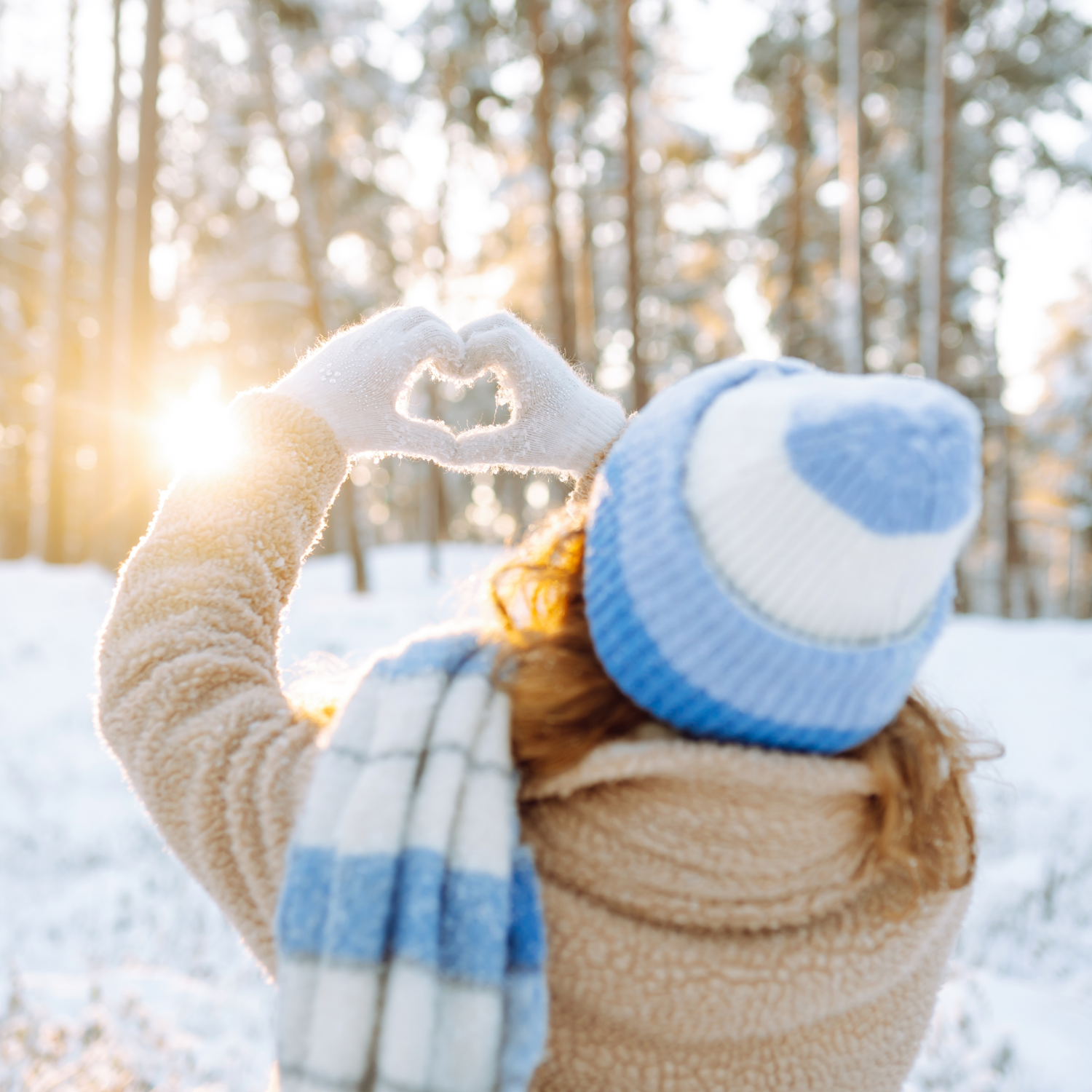 Kvinde i vinterlandskab laver hjertetegn med hænderne
