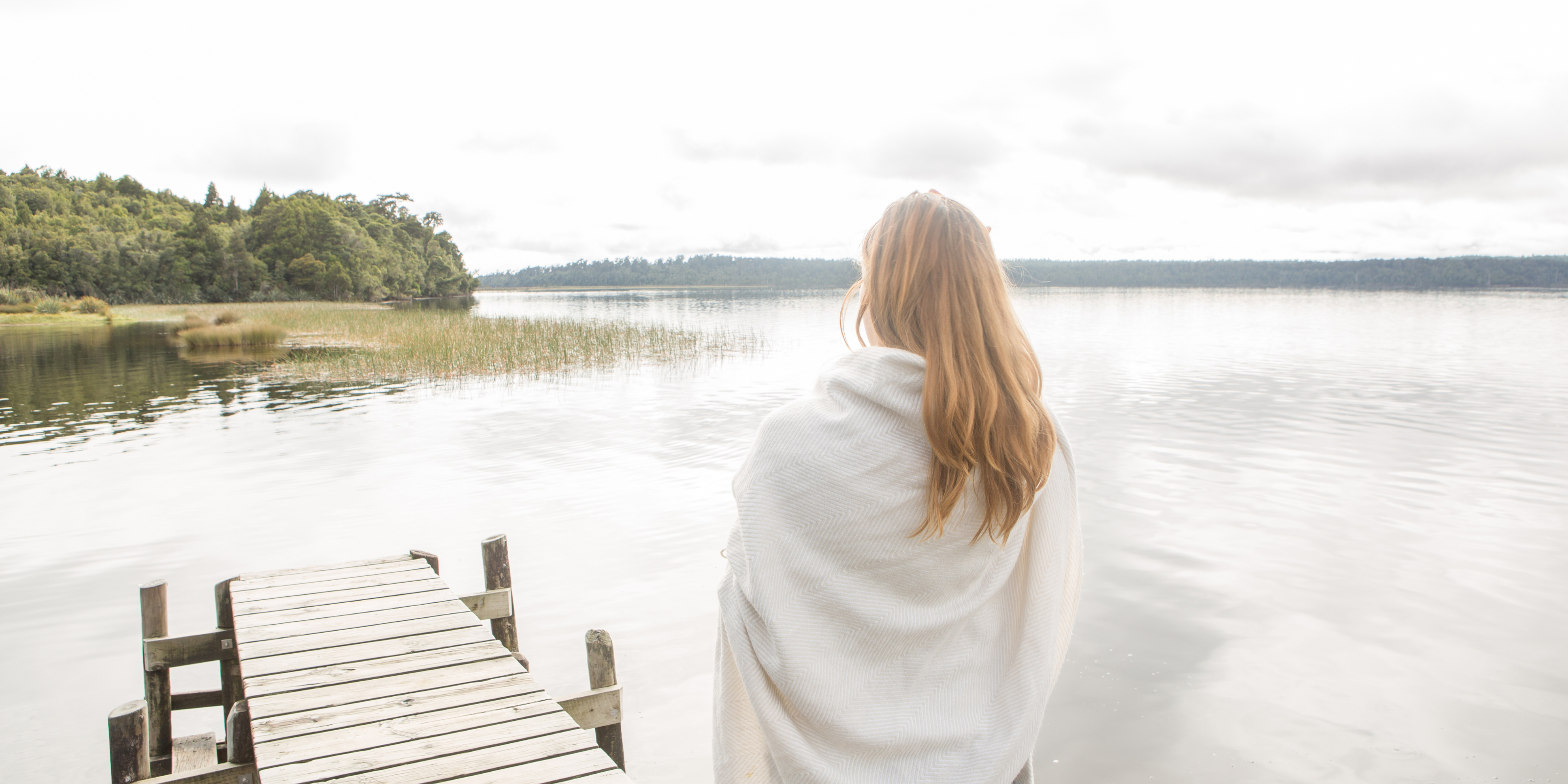 Kvinde på en badebro kigger ud over vandet